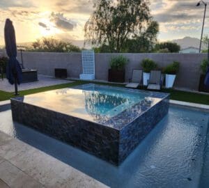 Backyard pool with lounge chairs at sunset.