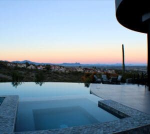 Infinity pool overlooking desert landscape at sunset.