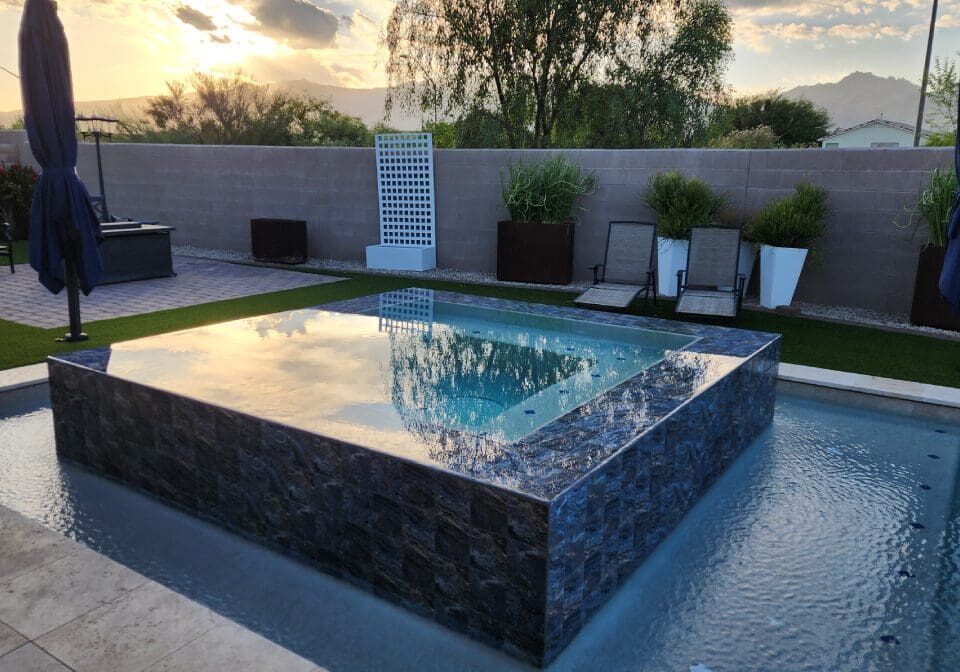 Backyard pool with lounge chairs at sunset.